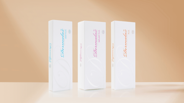 Three elegant white product boxes are displayed against a light peach gradient background. Each box features the brand name "DermaElla" in a stylish script, promoting their new dermalax dermal filler range. The left box has light blue text, the middle box has pink text, and the right box has orange text.