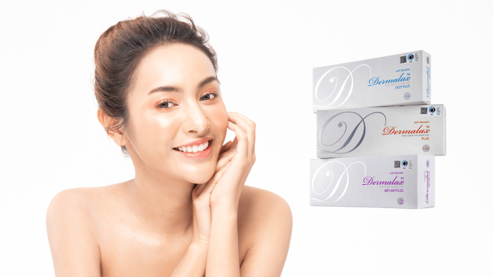 A woman with fair skin and a radiant smile poses with her hands gently touching her face. She has her hair tied back. To the right of the image are three skincare product boxes labeled "Dermalax" in different variants: Deep Plus, Plus, and Implant Plus—showcasing what Dermalax is used for.