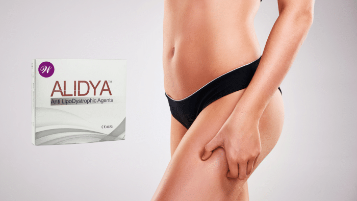 A person wearing black undergarments stands with their right hand on their thigh. To the left, there is a white box labeled "Alidya Anti LipoDystrophic Agents" prominently displayed, suggesting the product's use in cellulite treatment. Curious about its effectiveness? Check out Alidya reviews now!