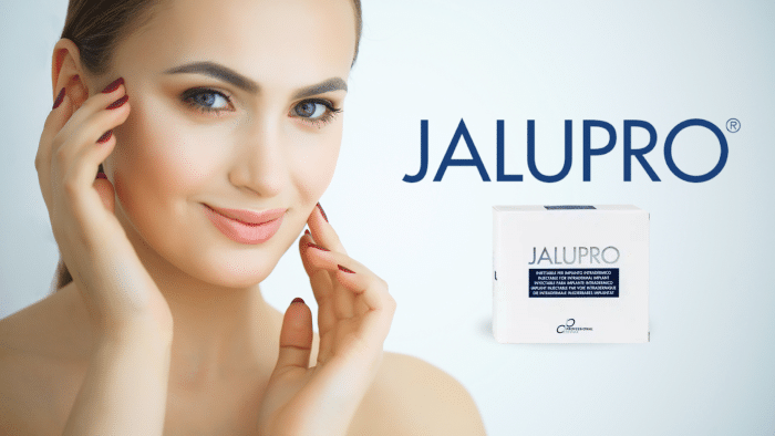 A person with clear skin and light makeup gently touches their face with both hands. The word "Jalupro" and an image of a Jalupro product box are displayed prominently next to the person on a light blue background, highlighting the benefits of Jalupro for radiant skin.