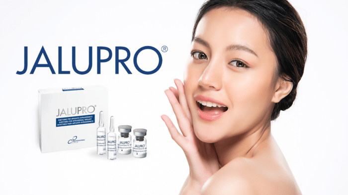 A woman with clear skin holds her hand to her face while smiling. Next to her, there are vials and a box labeled "JALUPRO," suggesting a skincare product. The brand name "JALUPRO" is prominently displayed in large text in the background, hinting at its lasting effectiveness.
