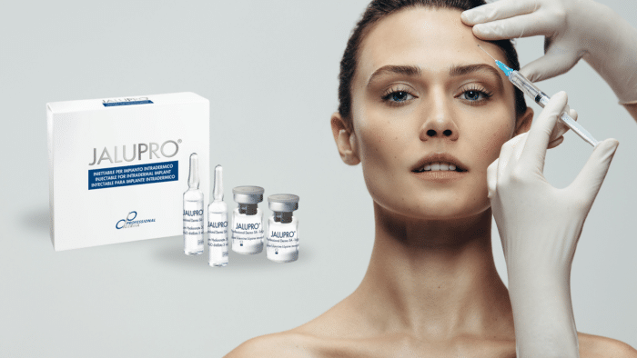 A person is receiving a cosmetic injection on the forehead. Products from the Jalupro line, including vials and ampoules, are visible on the left side of the image. The person administering the injection is wearing gloves. For those wondering, "Is Jalupro a filler?" this image offers some insight into its application.