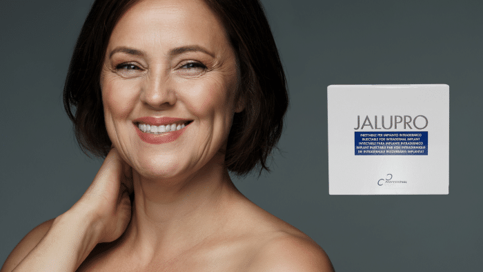 A woman with short brown hair, smiling and touching her neck, appears on the left side of the image against a gray background. To the right, there is a box labeled "Jalupro." The text on the box is partially obstructed but suggests a skincare product, hinting at its jalupro injection before and after benefits.
