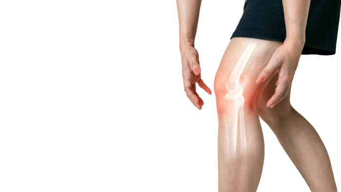 Person holding their knee with the bone structure revealed in an X-ray style illustration, highlighting the knee joint. The area around the knee is shown with a red glow, suggesting pain or inflammation. The image has a white background.