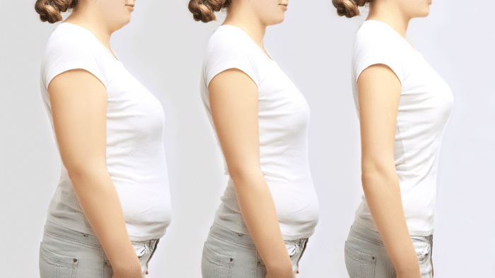A series of three side-profile images of a person with a progressively flatter and more toned stomach. The first image shows the most prominent belly, the middle image shows a moderately toned belly, and the third image shows a visibly flat stomach. The person wears a white T-shirt and grey jeans in all images.