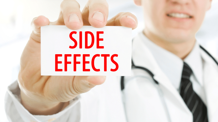 A doctor wearing a lab coat and stethoscope holds up a white card with "SIDE EFFECTS" written in bold red letters. The doctor's face is partially blurred in the background.